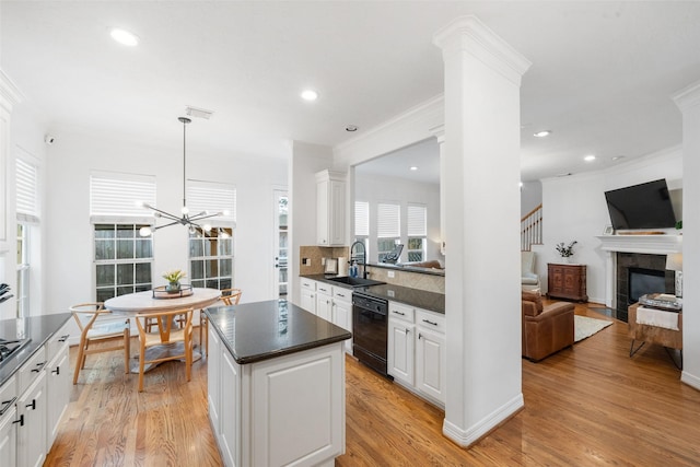 kitchen with crown molding, a sink, black dishwasher, and dark countertops