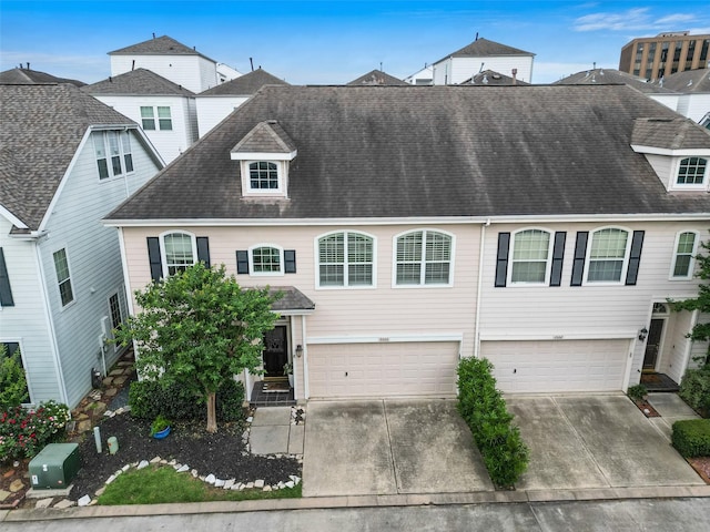 townhome / multi-family property with roof with shingles, driveway, and a garage