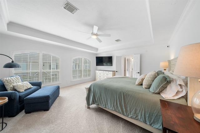 carpeted bedroom with visible vents, a raised ceiling, and ceiling fan