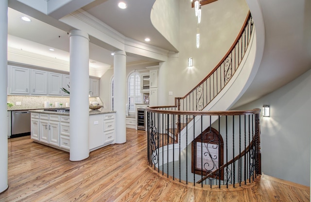 staircase featuring recessed lighting, wood finished floors, crown molding, and wine cooler