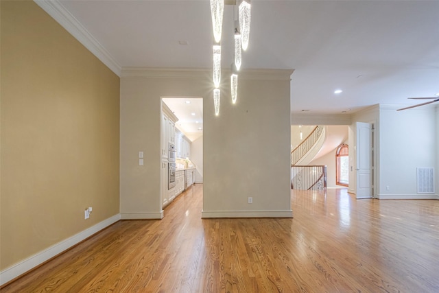 spare room with light wood-type flooring, visible vents, and ornamental molding