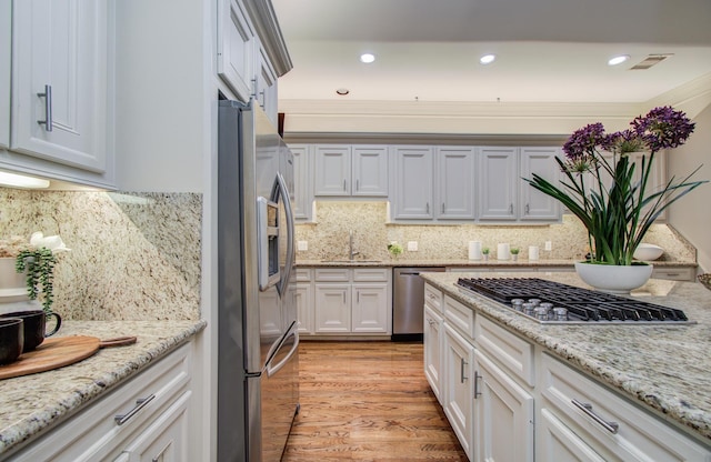 kitchen with light stone counters, appliances with stainless steel finishes, a sink, and visible vents