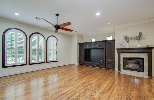 unfurnished living room with a fireplace with flush hearth, visible vents, light wood-style floors, a ceiling fan, and ornamental molding