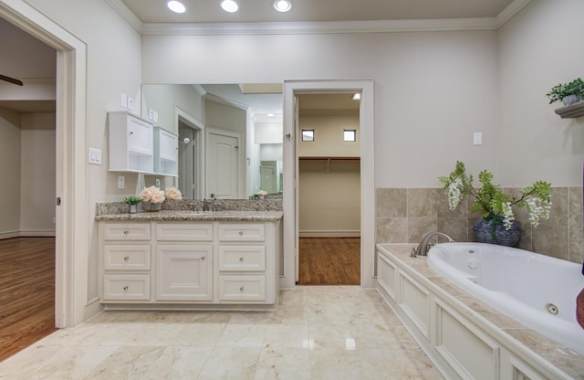 full bathroom with wood finished floors, vanity, a tub with jets, crown molding, and baseboards