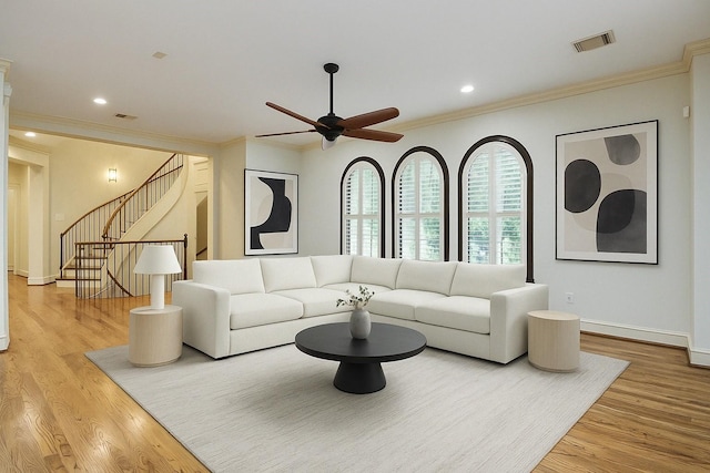 living area with wood finished floors, visible vents, stairs, and ornamental molding