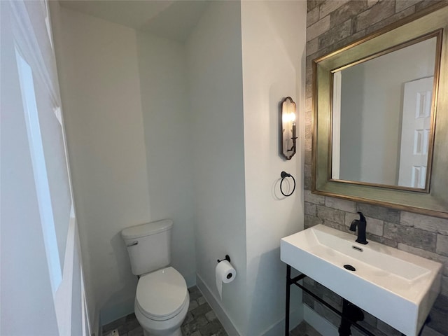 2520 Ohsfeldt St, Houston, TX 77008 - bathroom featuring toilet, baseboards, a sink, and stone finish floors