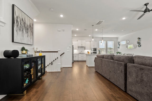 living area featuring visible vents, a ceiling fan, dark wood-type flooring, and recessed lighting