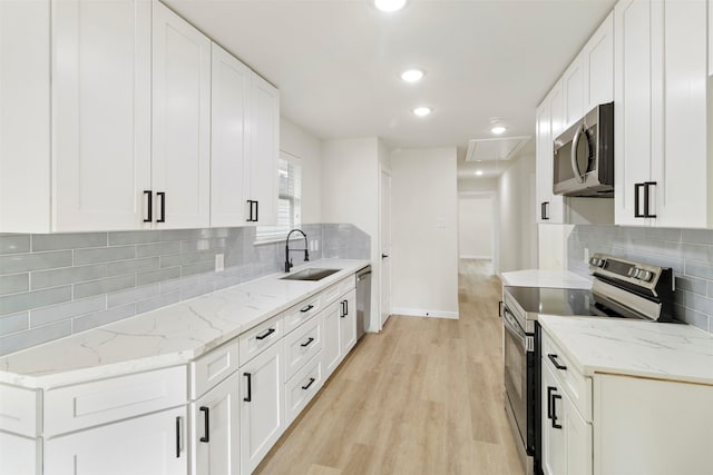 kitchen featuring stainless steel appliances, a sink, light wood-style floors, tasteful backsplash, and recessed lighting