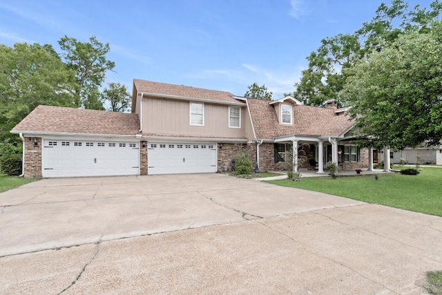 view of front of property with a front lawn, driveway, a shingled roof, covered porch, and an attached garage