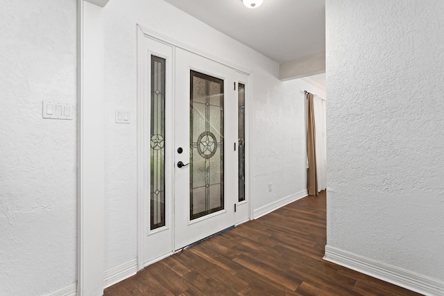 hall with dark wood-style flooring, a textured wall, and baseboards