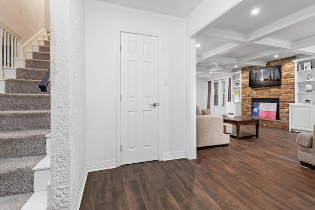 living room with baseboards, beamed ceiling, wood finished floors, stairway, and a stone fireplace