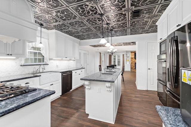 kitchen with an ornate ceiling, freestanding refrigerator, decorative backsplash, dishwashing machine, and a kitchen island