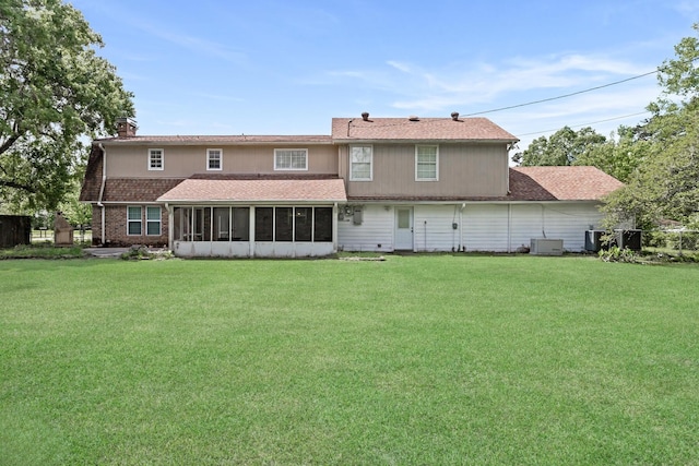 back of house with brick siding, a yard, a sunroom, and central AC unit