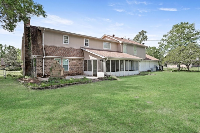 back of property with brick siding, a sunroom, a chimney, and a lawn