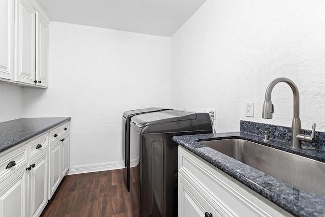 washroom with washer and clothes dryer, a sink, cabinet space, dark wood finished floors, and baseboards