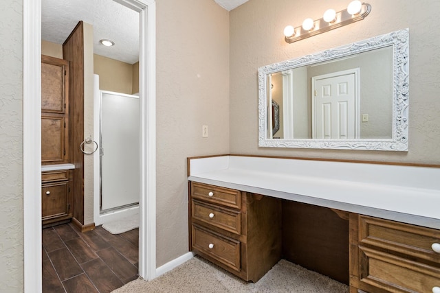 full bathroom with baseboards, vanity, a textured wall, and a shower stall