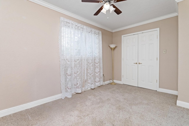 unfurnished bedroom with a closet, carpet floors, crown molding, and baseboards