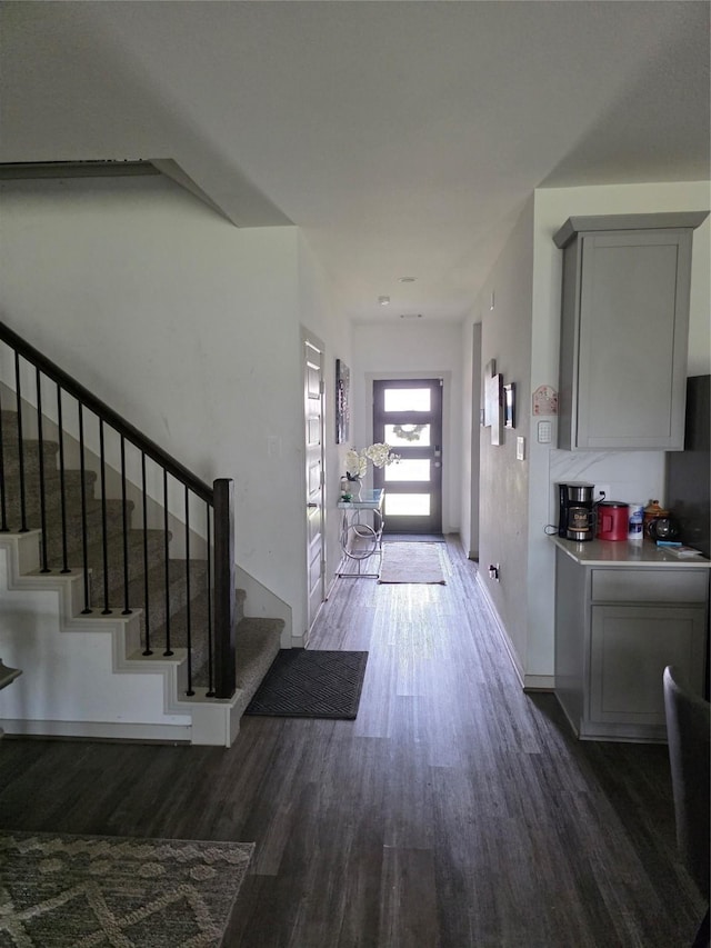 entrance foyer with baseboards, wood finished floors, and stairway