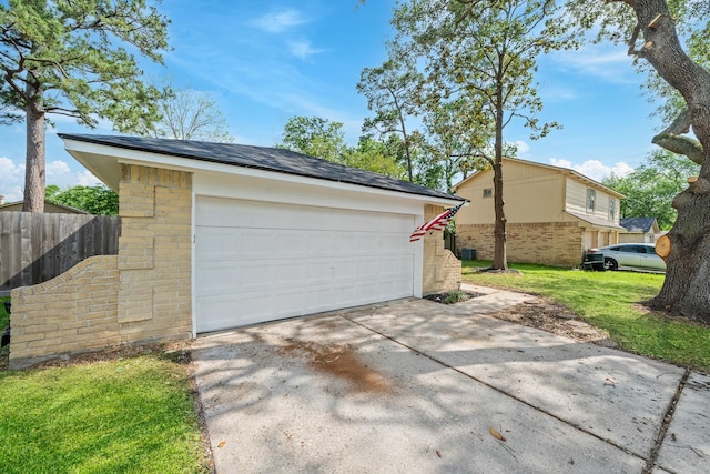 garage with concrete driveway and fence