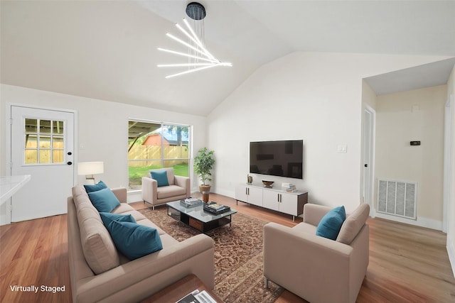 living room featuring wood finished floors, visible vents, an inviting chandelier, and high vaulted ceiling