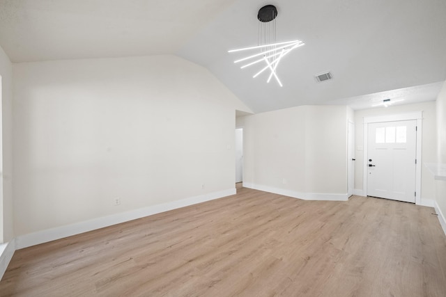 unfurnished living room with lofted ceiling, an inviting chandelier, visible vents, light wood-style floors, and baseboards