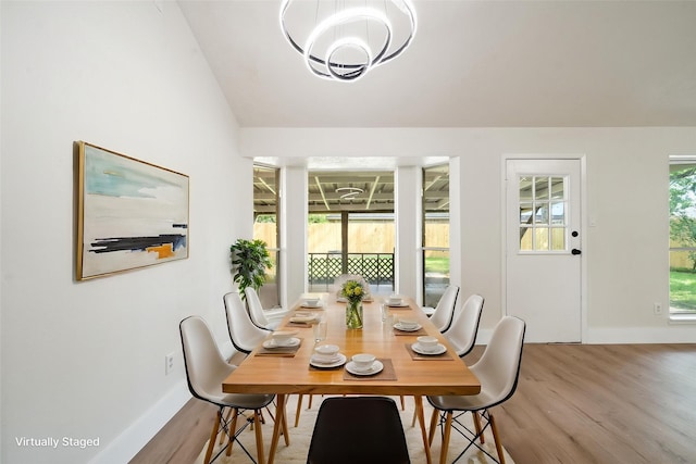 dining space featuring baseboards, vaulted ceiling, wood finished floors, and a chandelier