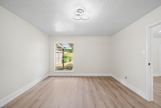 empty room with a textured ceiling and light wood finished floors