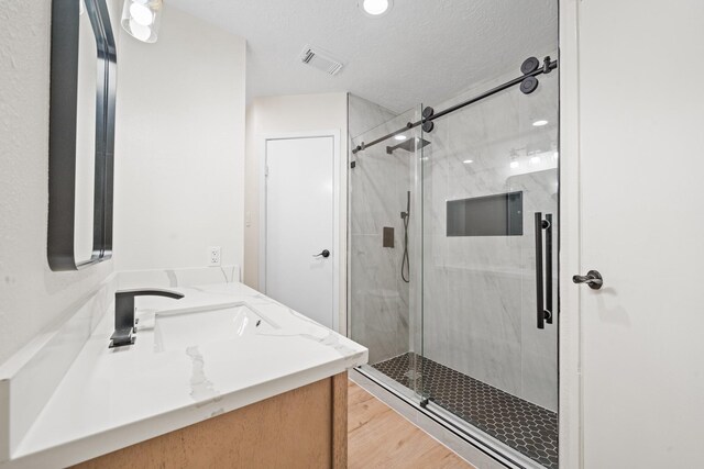 bathroom featuring wood finished floors, visible vents, vanity, and a stall shower