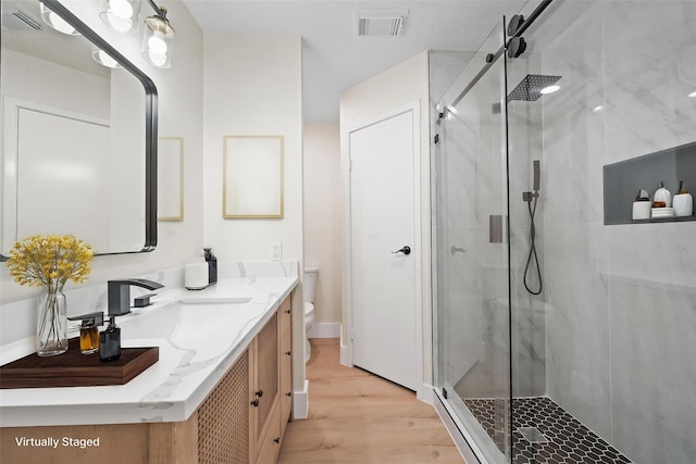 full bath featuring a shower stall, visible vents, toilet, and wood finished floors