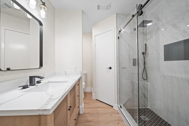 full bathroom with toilet, visible vents, wood finished floors, a shower stall, and vanity