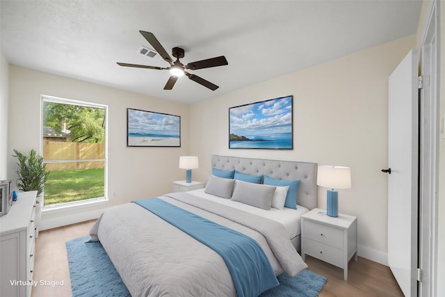 bedroom with baseboards, visible vents, light wood-style floors, and ceiling fan