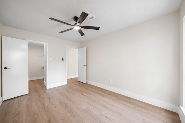 unfurnished bedroom with light wood-type flooring, a ceiling fan, baseboards, and visible vents
