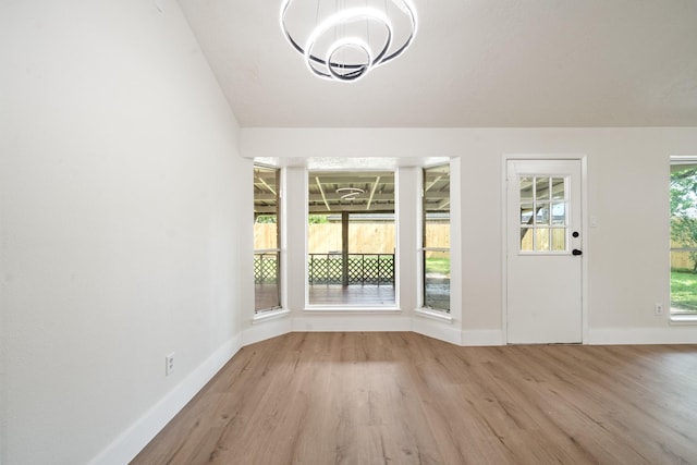 interior space featuring lofted ceiling, baseboards, wood finished floors, and a chandelier