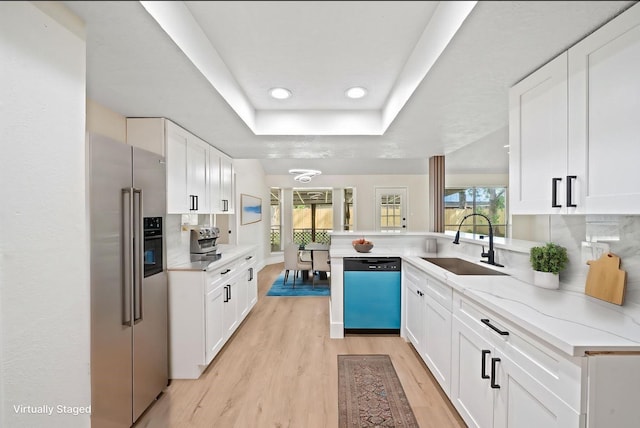 kitchen featuring light wood-style flooring, high end refrigerator, a sink, dishwashing machine, and a raised ceiling