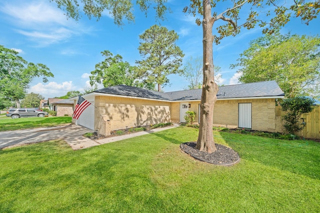 exterior space featuring concrete driveway, an attached garage, fence, and a yard