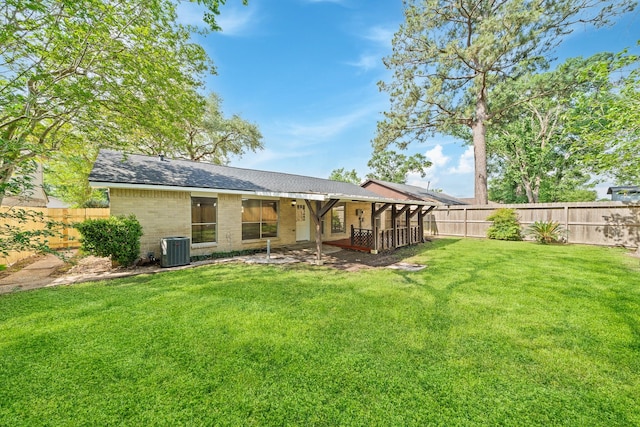 back of property featuring central AC unit, a shingled roof, a fenced backyard, a yard, and brick siding