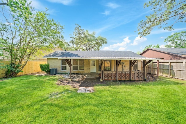 back of property featuring a fenced backyard, brick siding, a yard, and central AC