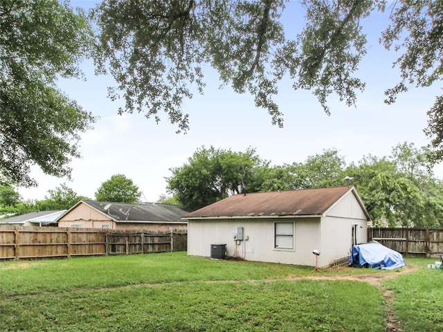 rear view of property featuring central AC, a yard, and a fenced backyard