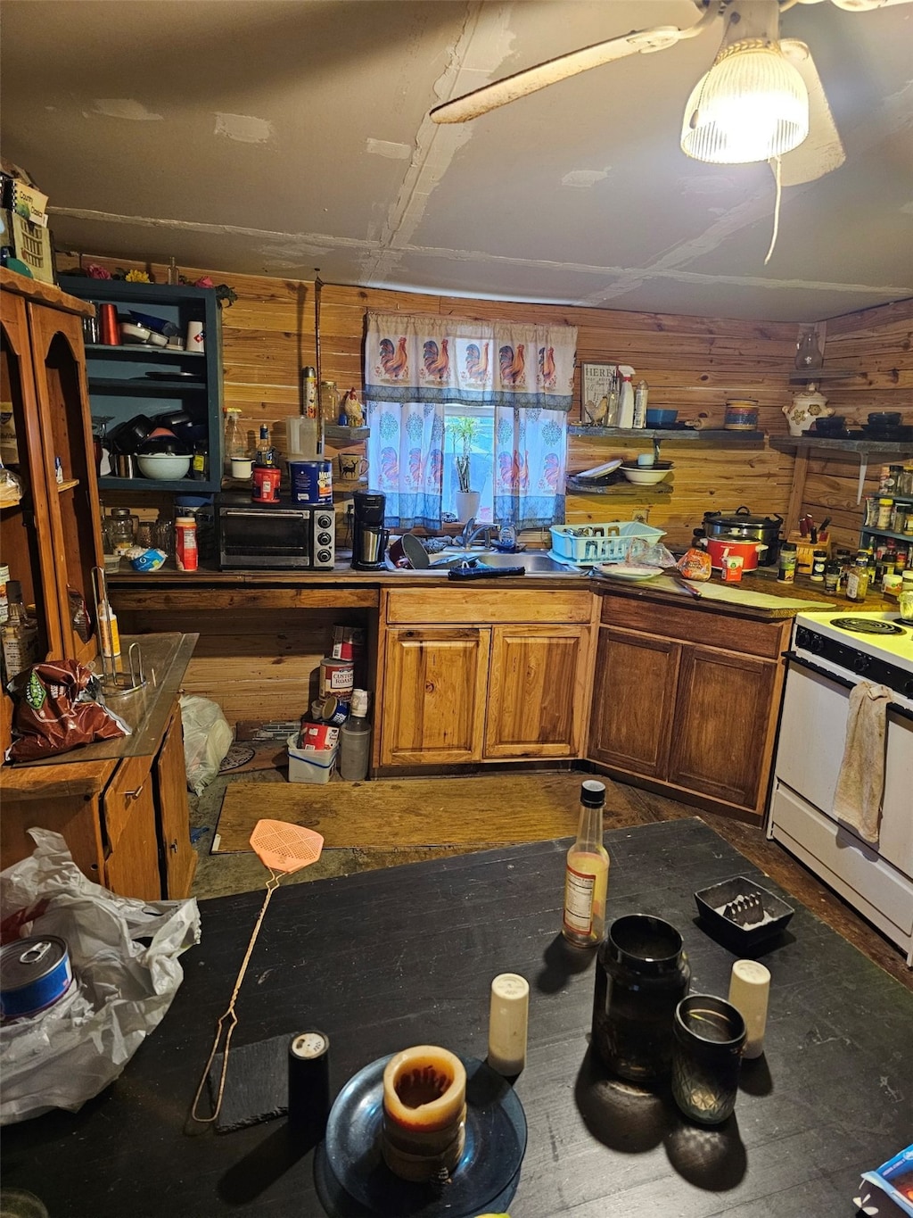 kitchen with white electric range oven, a toaster, a sink, wood walls, and brown cabinets