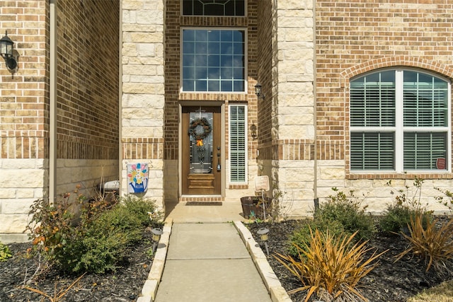 view of exterior entry featuring brick siding and stone siding