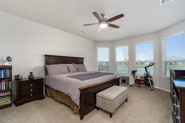 bedroom featuring a ceiling fan, baseboards, light colored carpet, and multiple windows