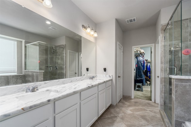 bathroom featuring a sink, double vanity, visible vents, a shower stall, and a walk in closet
