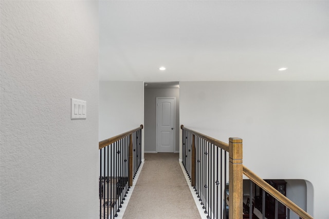 hallway featuring recessed lighting, a textured wall, an upstairs landing, carpet floors, and baseboards