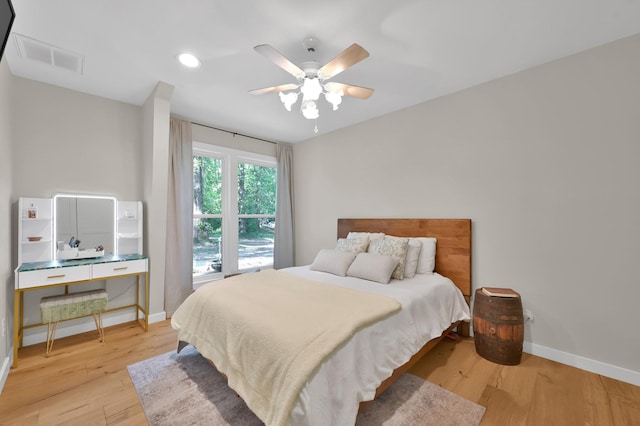 bedroom with wood finished floors, visible vents, a ceiling fan, and baseboards