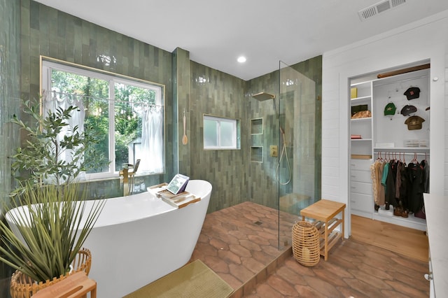 full bath with a soaking tub, plenty of natural light, visible vents, and a walk in shower