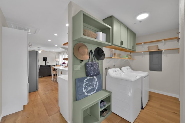 washroom featuring washing machine and clothes dryer, cabinet space, electric panel, and light wood finished floors