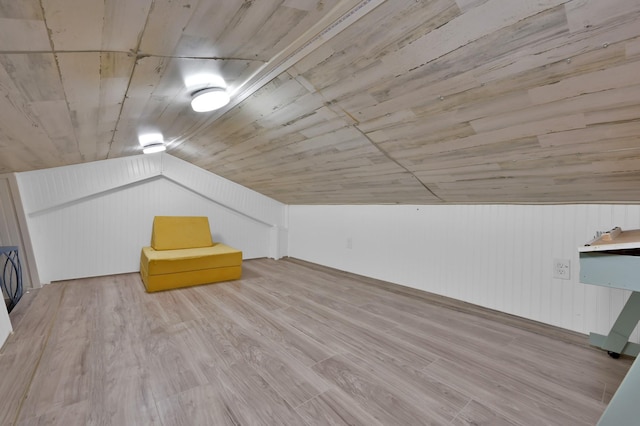 additional living space with lofted ceiling, wood walls, and wood finished floors