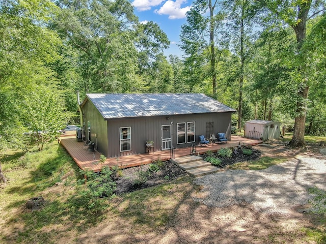 back of house featuring a wooden deck, an outbuilding, a storage shed, and metal roof