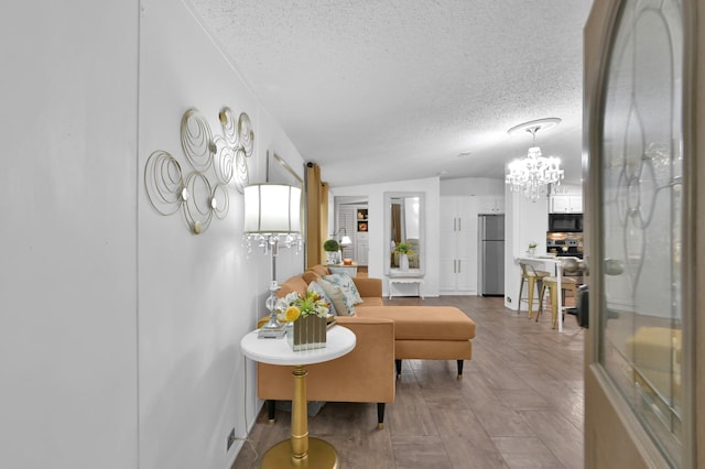 living area with vaulted ceiling, a textured ceiling, and a notable chandelier
