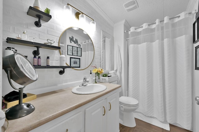bathroom featuring a sink, a textured ceiling, backsplash, wood finished floors, and ornamental molding